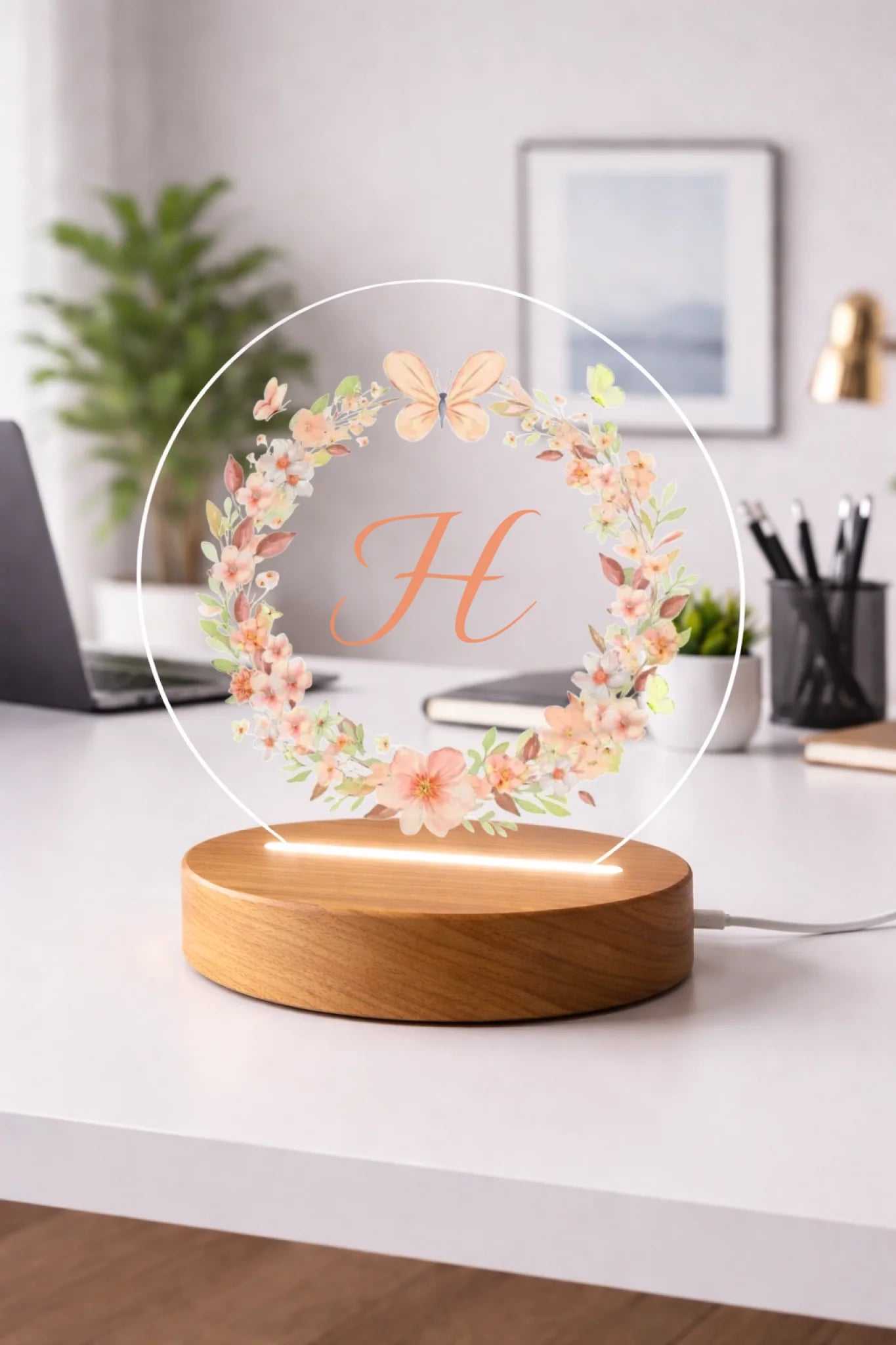 Decorative lamp with floral design and letter 'H' on a table in a cozy room.