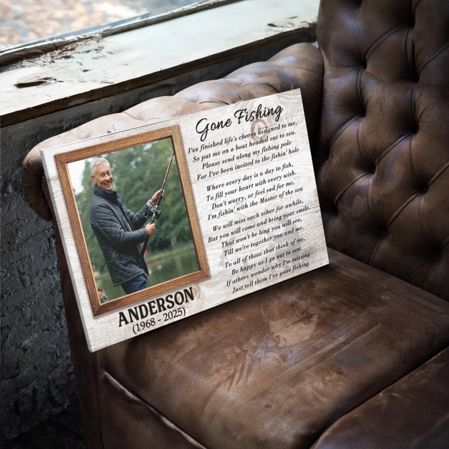 A rectangular canvas print featuring a photo of a man fishing, a poem, and a name, resting on a brown leather armchair.