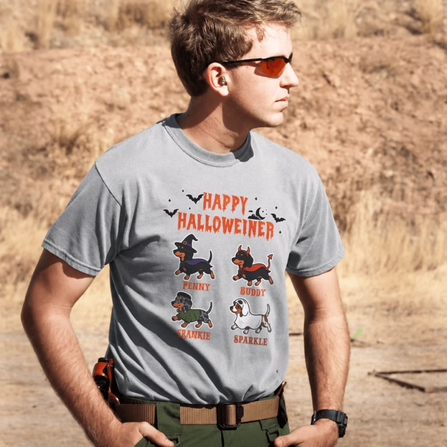 A man wearing a grey Happy Halloweiner t-shirt featuring four cute dachshund dogs in various Halloween costumes.