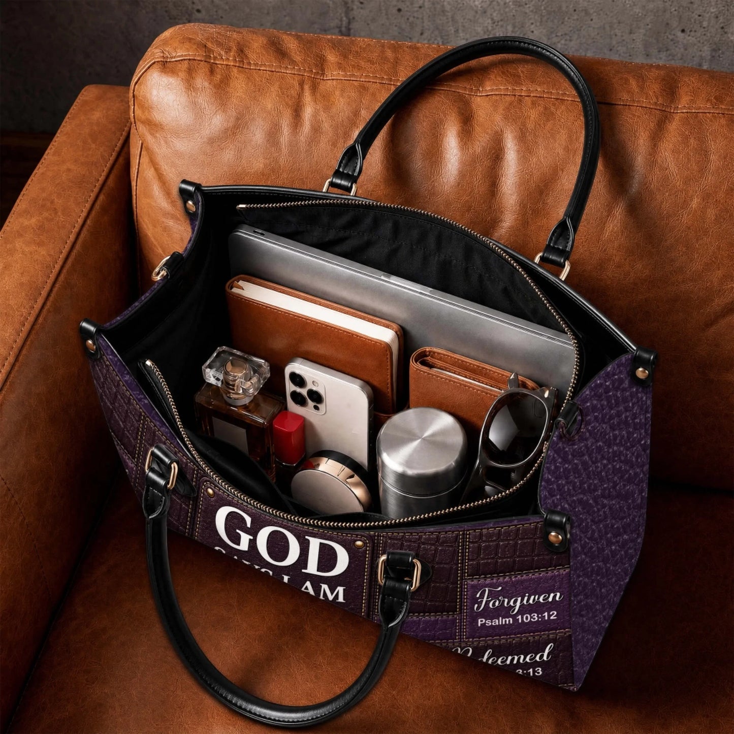 Spacious interior of a personalized Christian handbag filled with daily essentials like a laptop, phone, and cosmetics.
