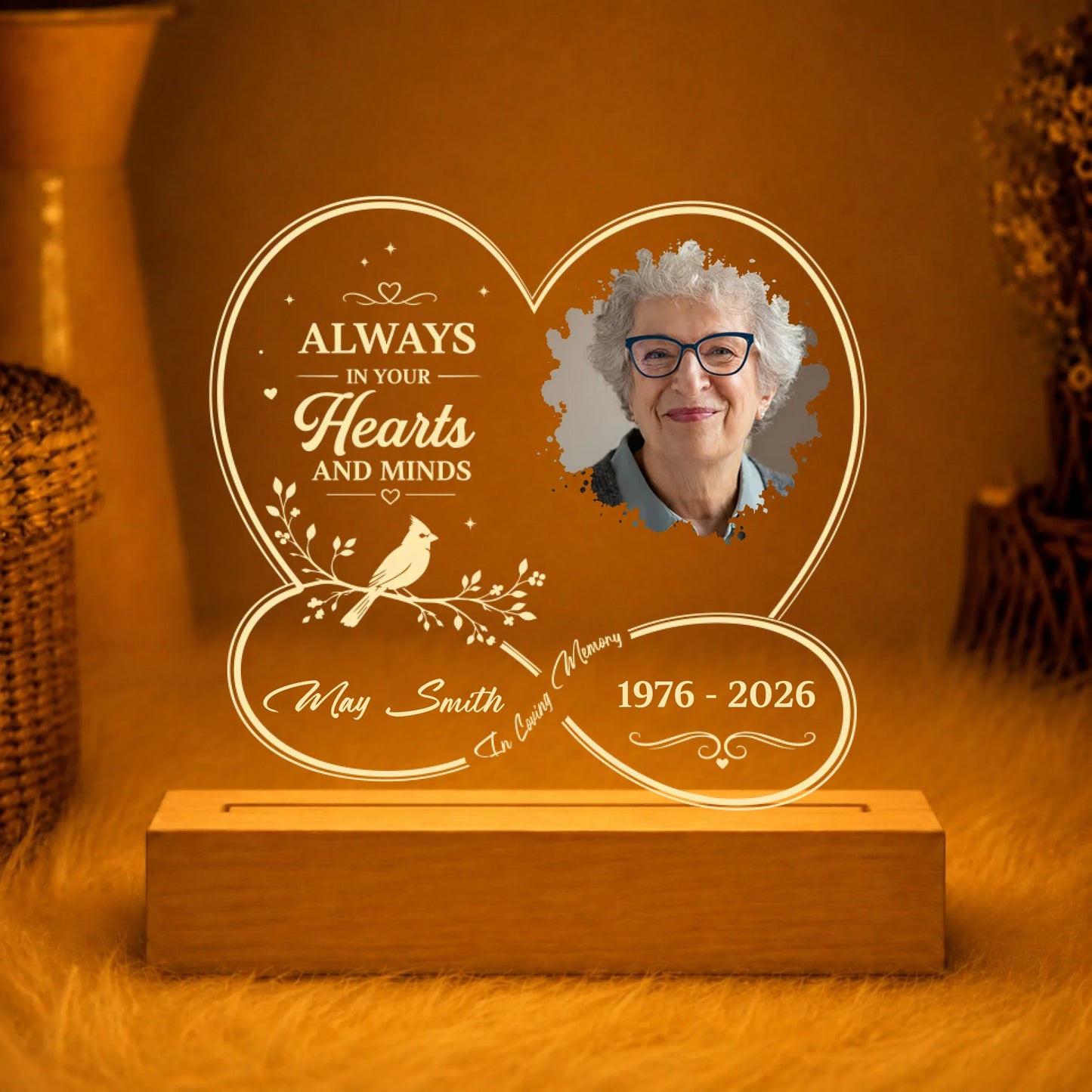 Engraved heart shaped LED memorial light with custom photo and dates displayed on a wooden stand for remembrance.