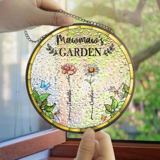 Decorative glass panel with 'Mama Garden' text and floral designs, hanging against a blurred greenery background.