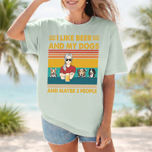 Person wearing a light green t-shirt with a graphic and text about beer and dogs, standing on a beach.