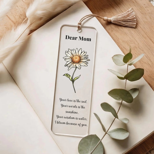 Decorative bookmark with a sunflower illustration and text on a wooden surface with leaves.