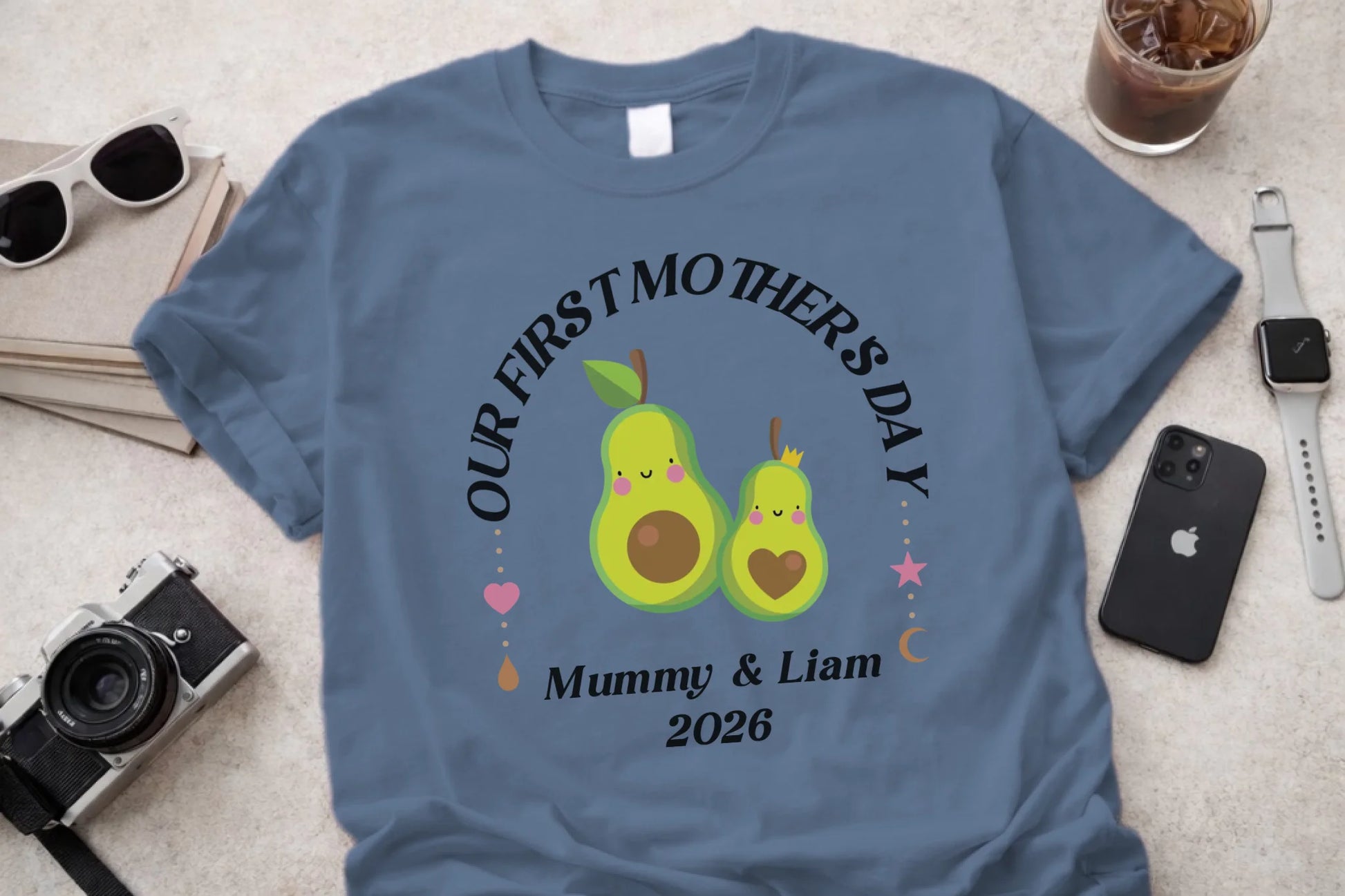 Blue t-shirt with avocado design and text on a light surface with accessories.