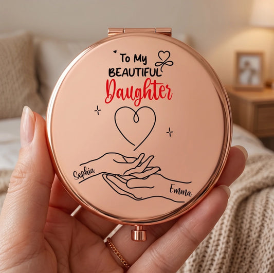 Rose gold compact mirror with 'To My Beautiful Daughter' text and hand illustration held by a person.