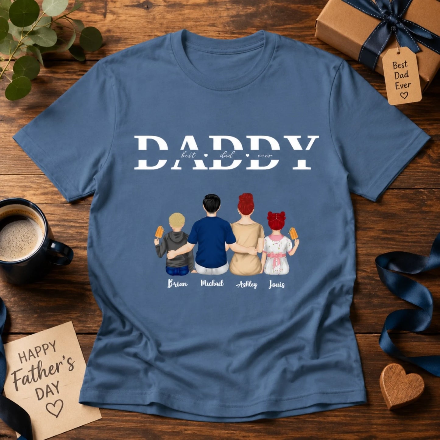 Blue t-shirt with family illustration and 'Daddy' text on a wooden surface with Father's Day decorations.