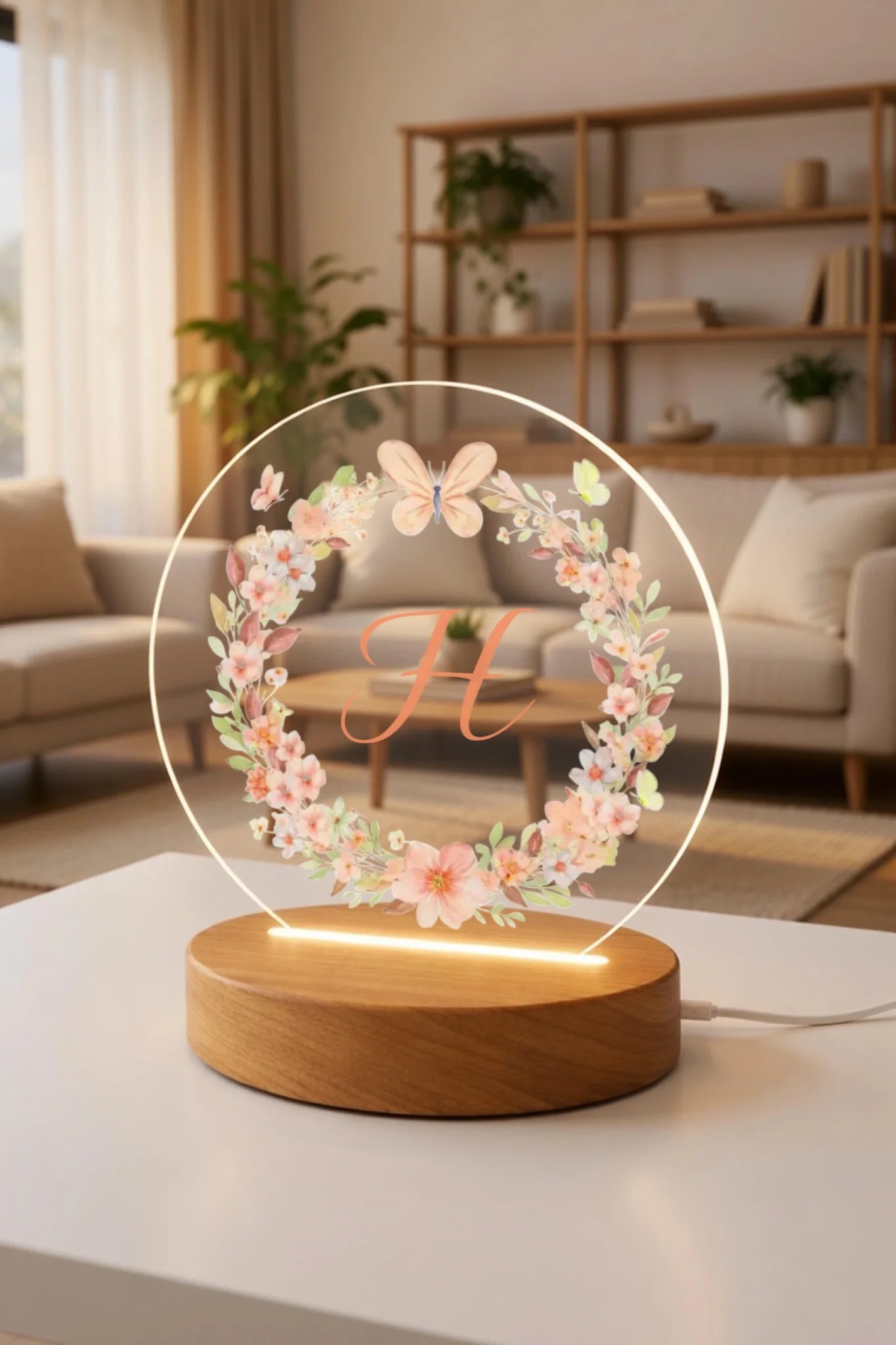 Decorative lamp with floral design and letter 'H' on a table in a cozy room.
