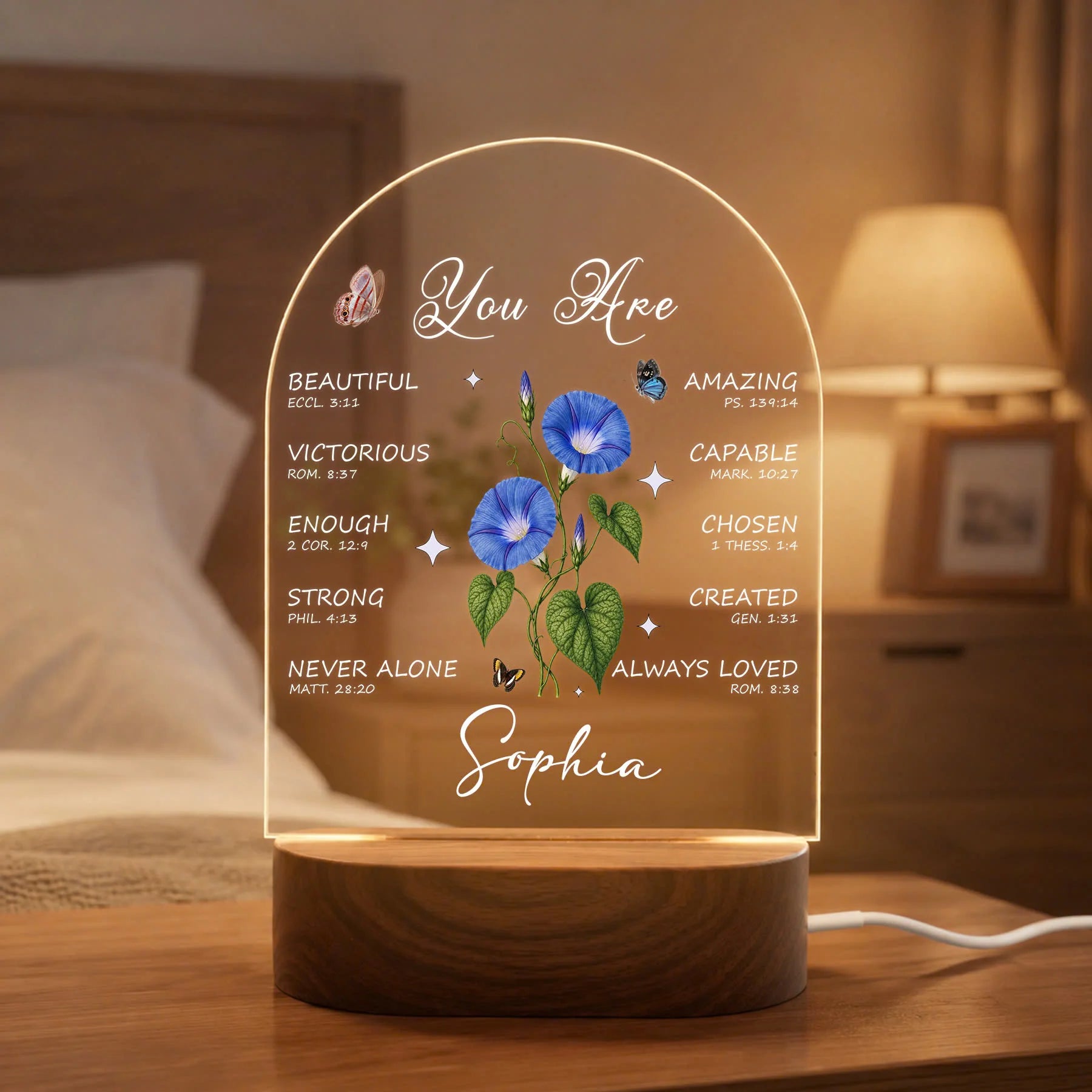Decorative lamp with motivational phrases and floral design on a wooden base, placed on a nightstand.
