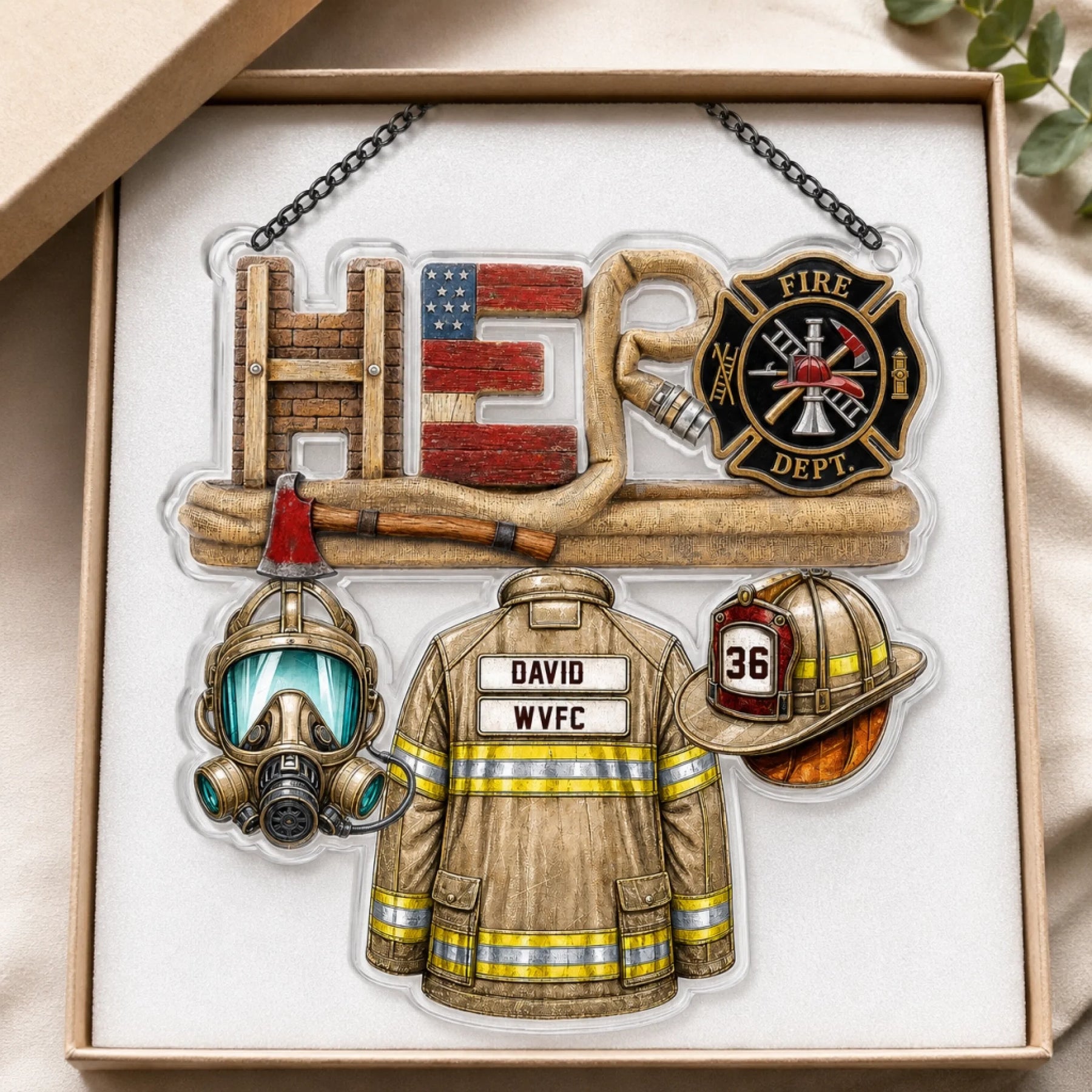 An acrylic ornament featuring firefighter gear and the word "HERO" in a gift box with white foam padding.