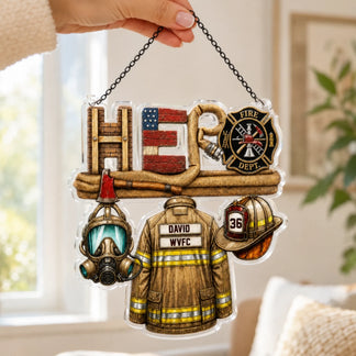 A person's hand holds up a clear acrylic "HERO" ornament, showcasing firefighter elements like a coat and helmet.