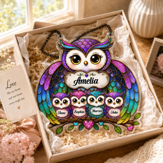 A vibrant, glittery owl family acrylic hanging sign with names "Amelia", "Jane", "Sophia", "Marcus", and "Jake" inside a gift box with a card.