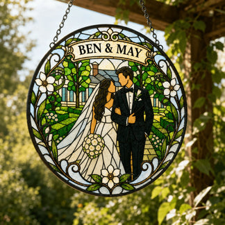 A round stained glass style sign features a bride and groom in a garden with a house. 'BEN & MAY' is on a banner at the top, suspended by a chain.