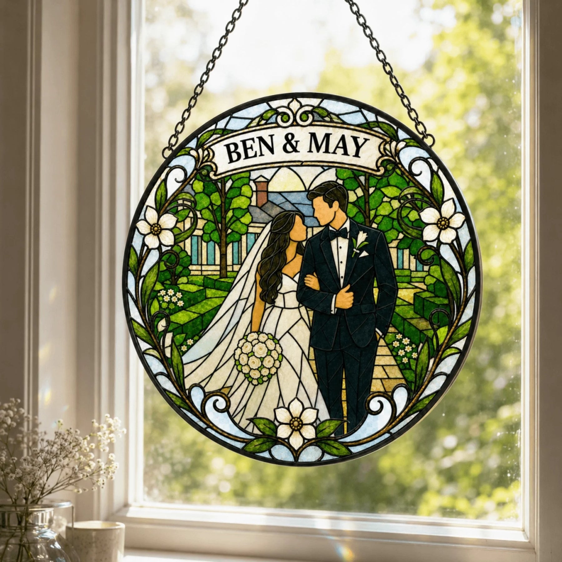 A round stained glass suncatcher depicts a wedding couple walking through a garden scene with a house. A banner reads 'BEN & MAY'.