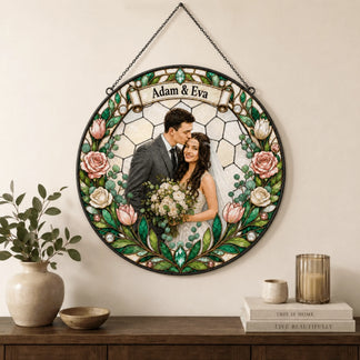 A circular stained-glass style ornament featuring a couple's photo hangs on a wall above a wooden dresser with decor.