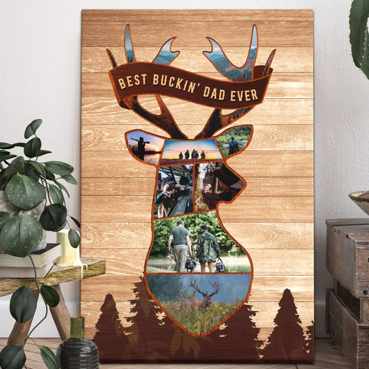 Vertical canvas print featuring a deer head photo collage, a banner reading "BEST BUCKIN' DAD EVER", and dark pine trees, displayed next to a houseplant and wooden crates.