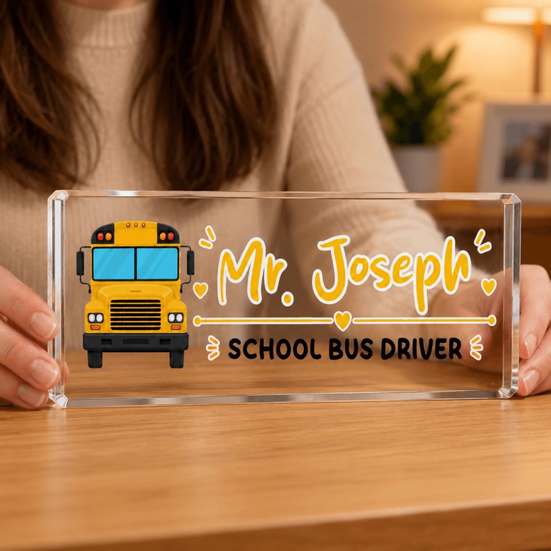 A person holds a clear rectangular acrylic block with a yellow school bus illustration and "Mr. Joseph School Bus Driver" text.