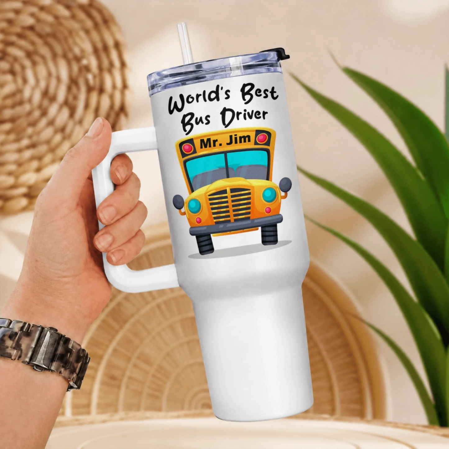 A hand holding a white handled tumbler with a yellow school bus graphic and "World's Best Bus Driver Mr. Jim" text.