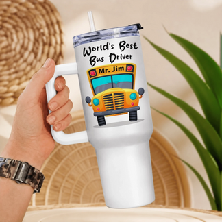 A hand holding a white handled tumbler with a yellow school bus graphic and "World's Best Bus Driver Mr. Jim" text.