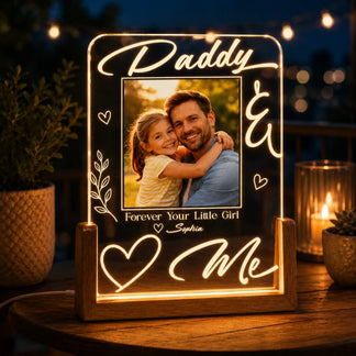 Decorative light sign with a photo of a man and a child, surrounded by decorative elements on a wooden surface.
