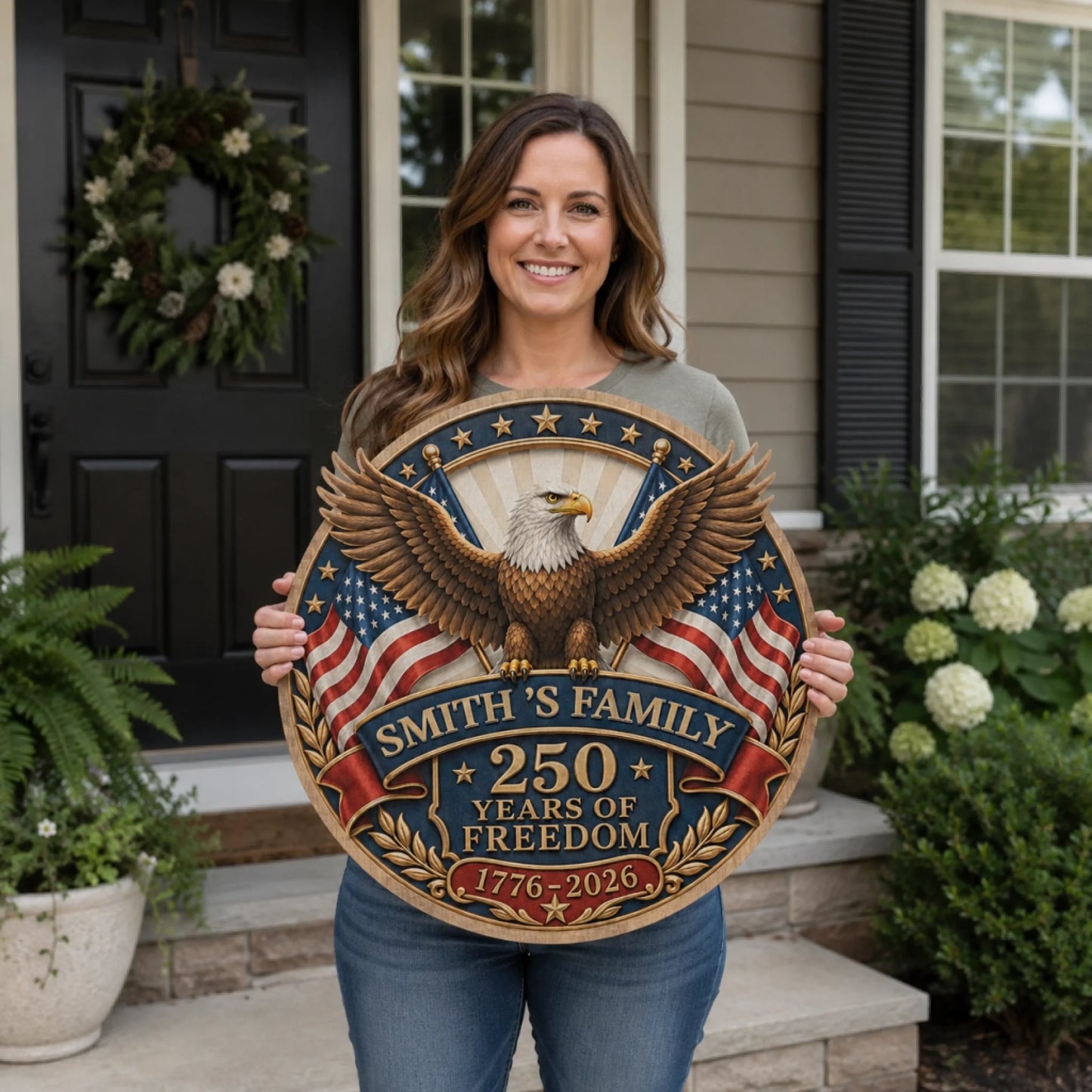 Woman holding a decorative sign with an eagle and American flag design, standing on a porch.