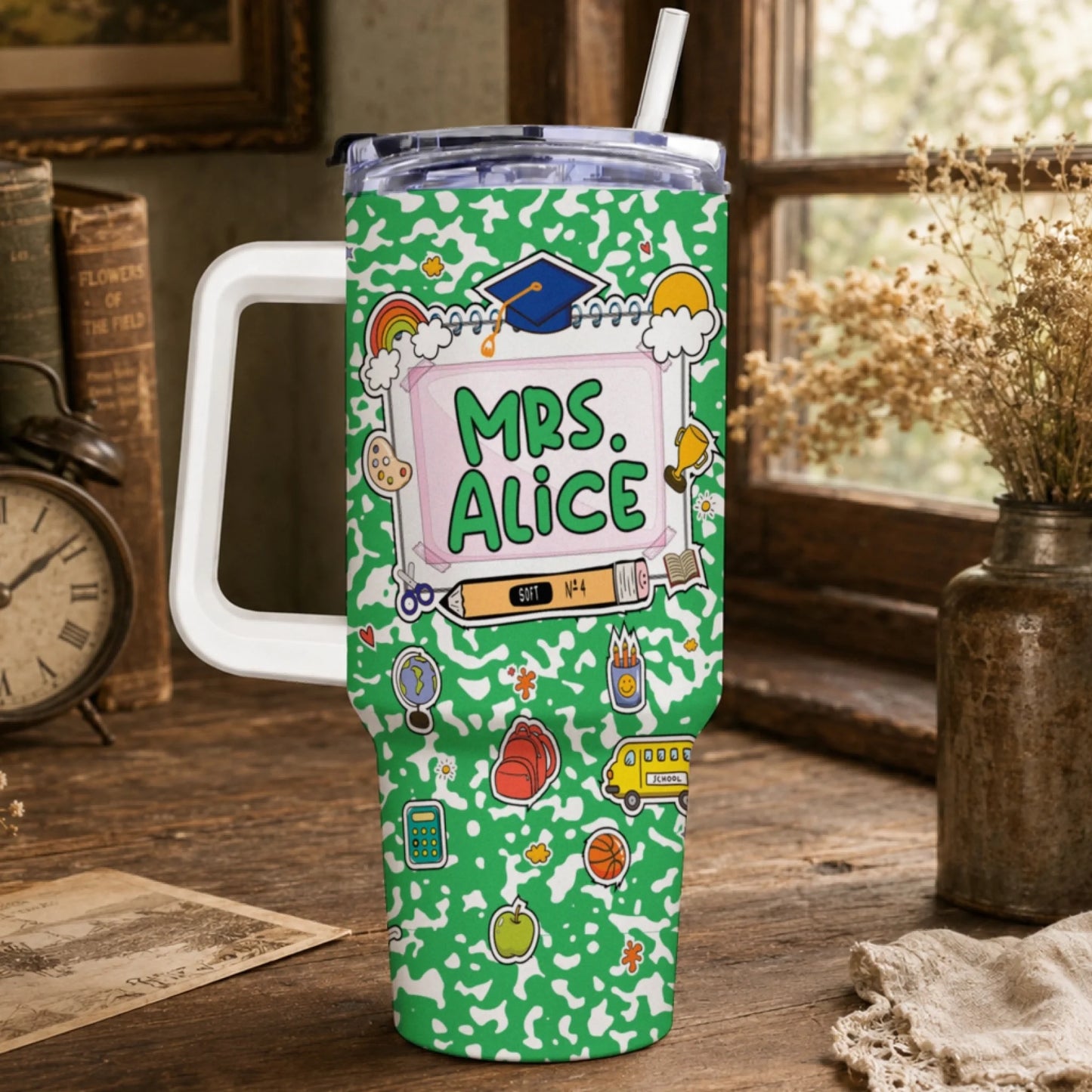 Green travel tumbler with a white handle, lid, and straw. It features a school-themed design with 'MRS. ALICE' and various colorful illustrations.