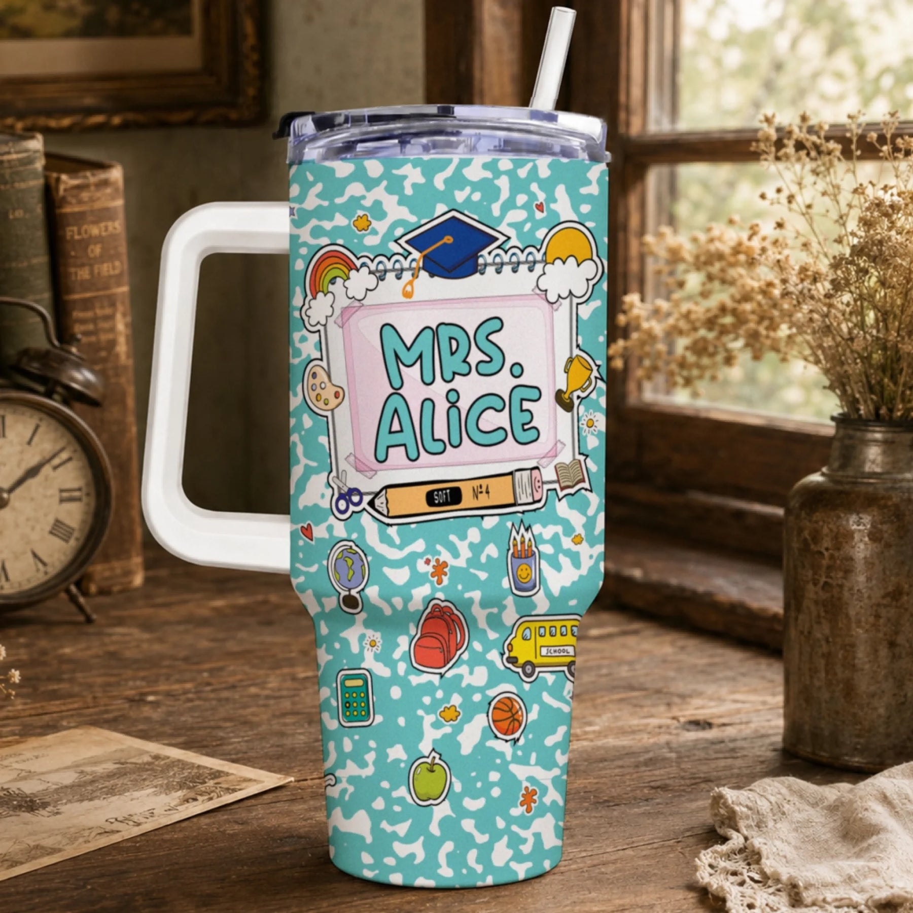 Light blue travel tumbler with a white handle, lid, and straw. It features a school-themed design with 'MRS. ALICE' and various colorful illustrations.