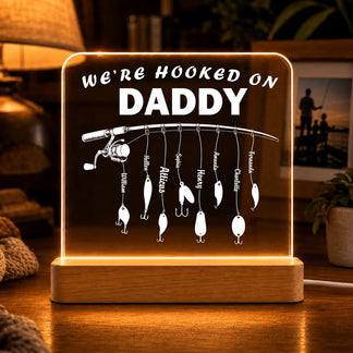 Decorative lamp with fishing theme and 'We're Hooked on Daddy' text on a wooden base.
