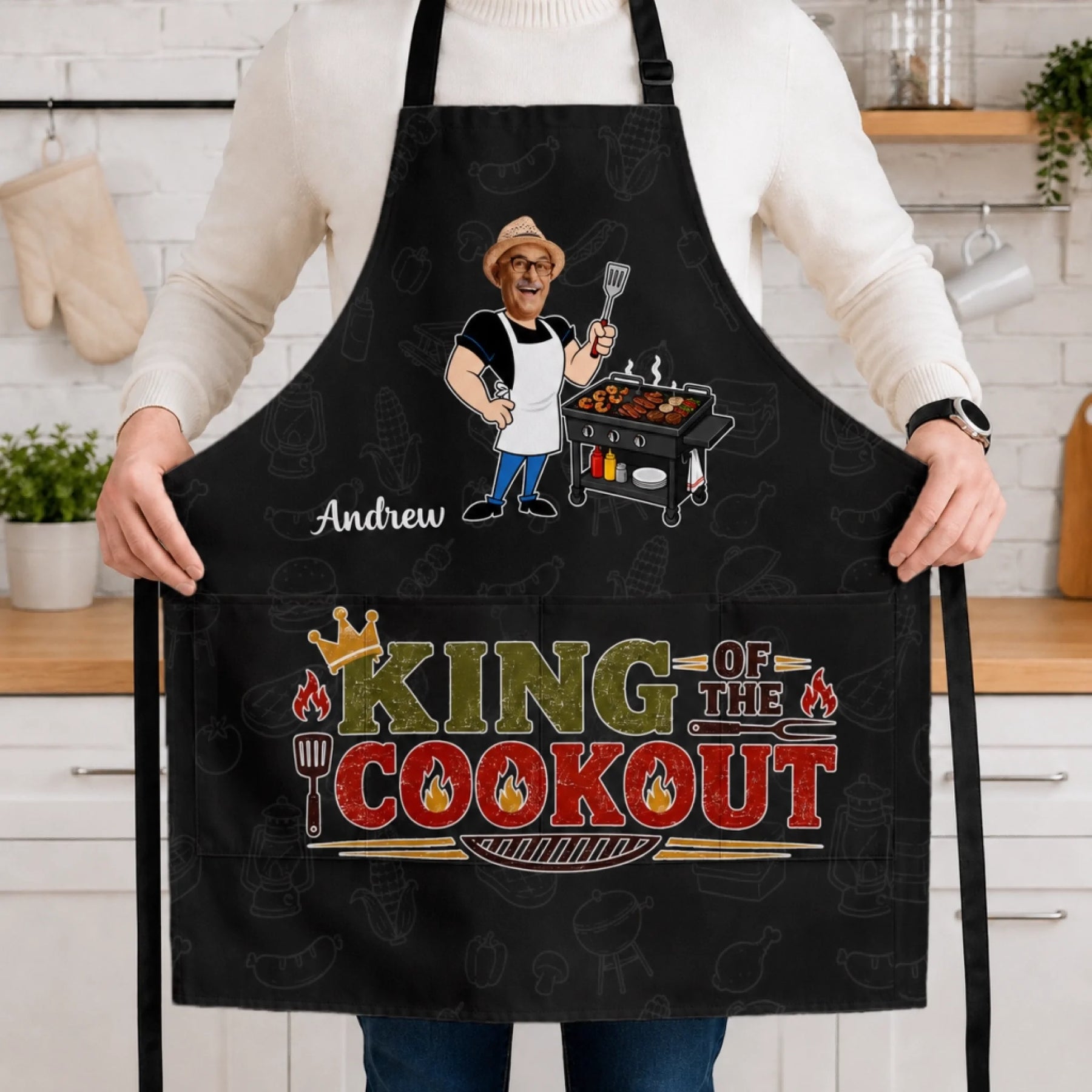 Person wearing a black apron with 'King of the Cookout' design in a kitchen.