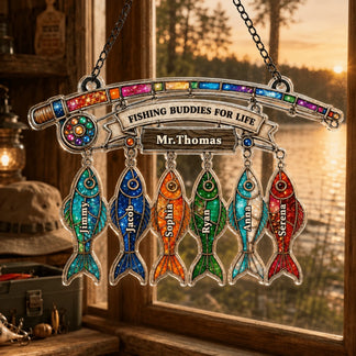 Decorative hanging sign with colorful fish-shaped charms and 'Fishing Buddies for Life' text, set against a window view of a sunset.