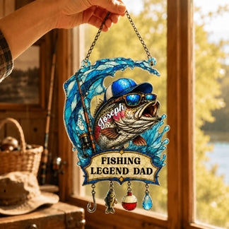 Decorative sign with a fish design and 'Fishing Legend Dad' text, held by a hand indoors.