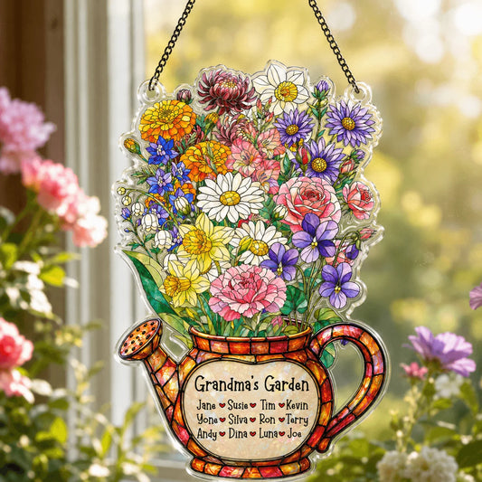 Decorative stained glass panel of a watering can with flowers and 'Grandma's Garden' text, hanging outdoors.