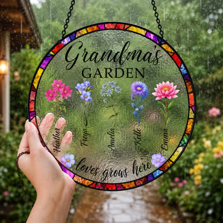 Round stained glass panel with floral designs and text held in front of a garden.