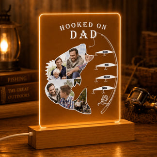 LED sign shaped like a fish with 'Hooked on Dad' text and family photos, placed on a wooden surface.