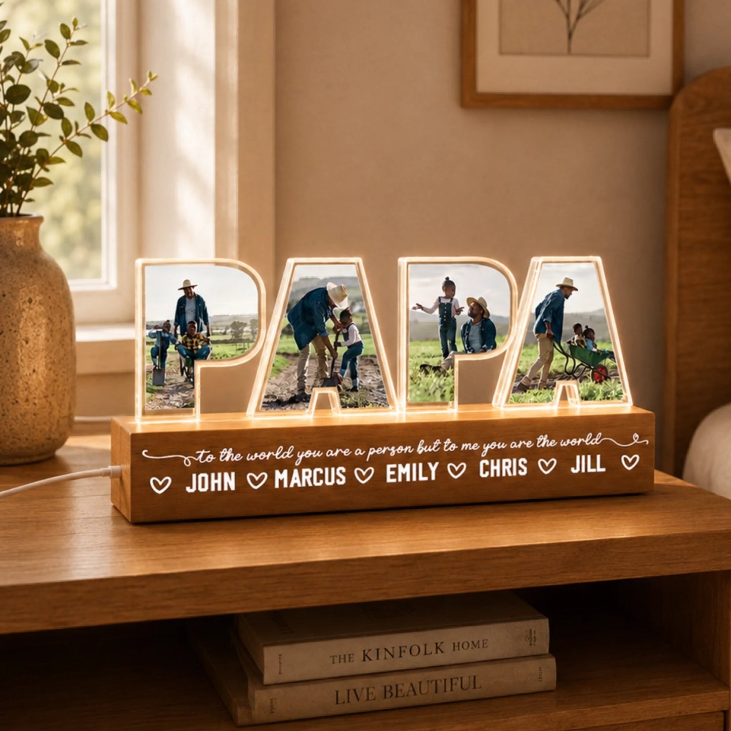 Decorative wooden sign with illuminated letters displaying family photos and names on a wooden surface.
