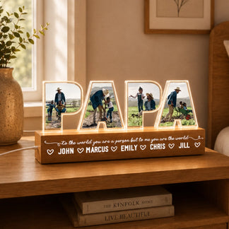Decorative wooden sign with illuminated letters displaying family photos and names on a wooden surface.