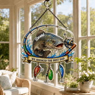 Decorative wall hanging with fish and 'We Hooked the Best Dad' text in a sunlit room.