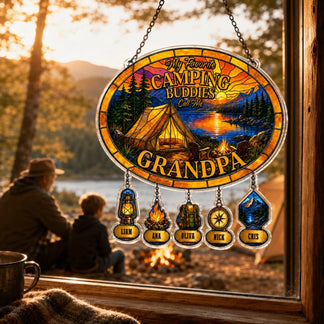 Decorative sign with camping design and names hanging by a window with a view of a lake and mountains.