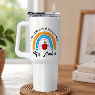 A white handled tumbler with a clear lid and straw, featuring a rainbow design, red apple, and 'Mrs. Amber' text.
