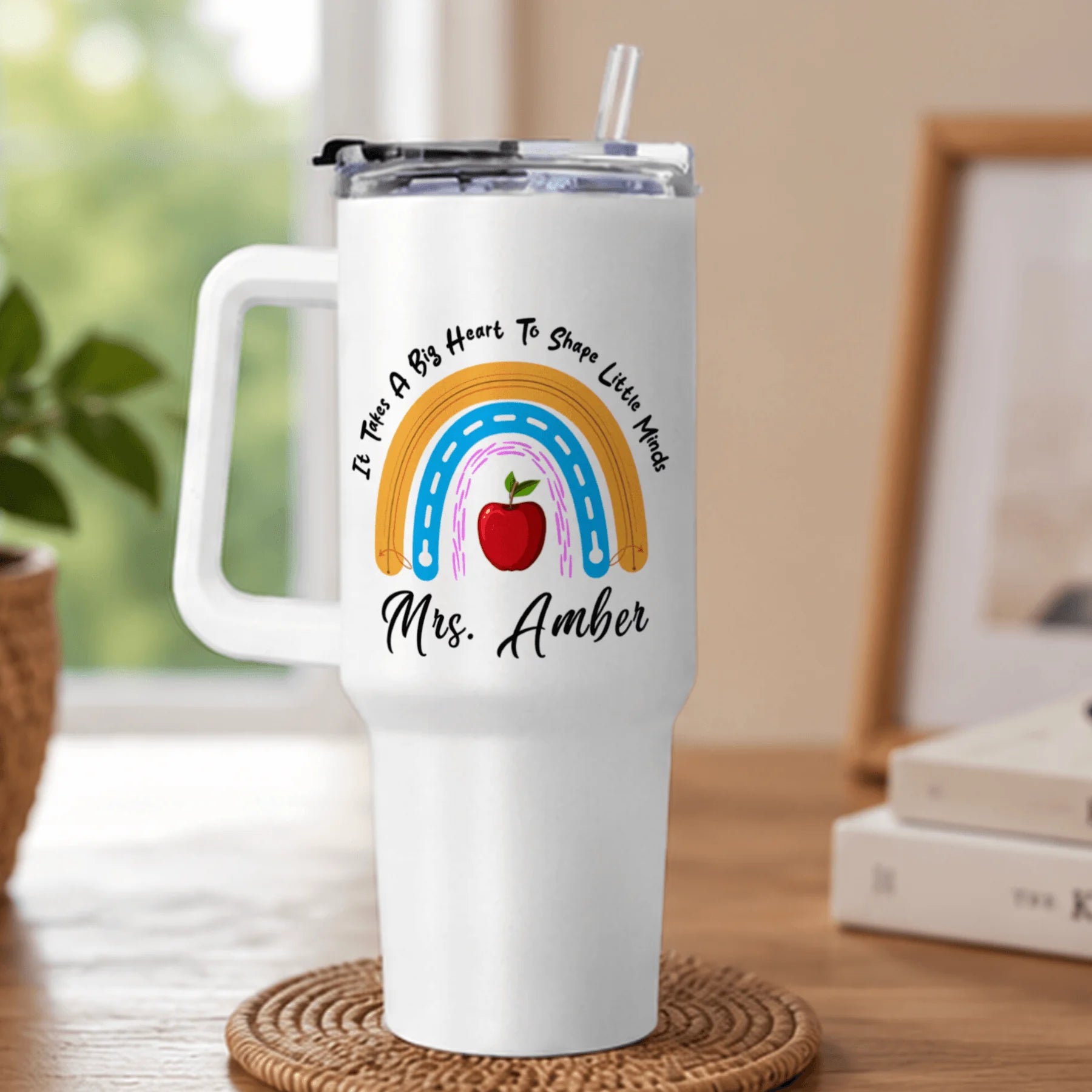 White tumbler with rainbow, apple, and text design on a wooden surface.