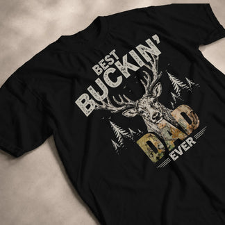Black cotton t-shirt featuring a deer head, forest landscape, and Best Buckin Dad Ever text for a stylish hunting fan.
