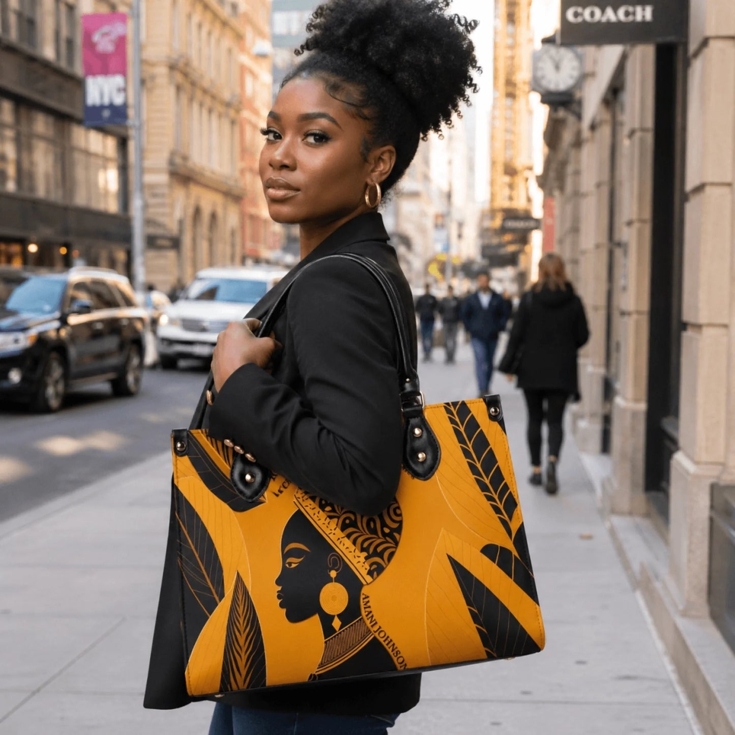 Stylish gold and black handbag with cultural art carried by a woman wearing a black blazer in the city