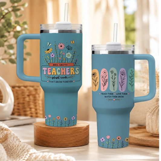 Set of two light blue stainless steel tumblers with floral teacher appreciation designs, straws, and handles.