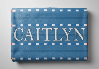 Folded personalized beach towel with a blue swim lane and white line pattern featuring the custom name Caitlyn.