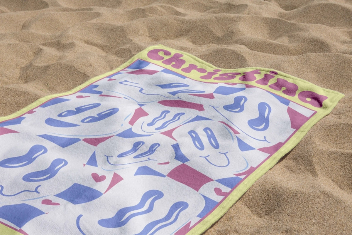 Soft personalized beach towel with the name Christina, featuring a vibrant wavy smiley face design for sunny vacations.