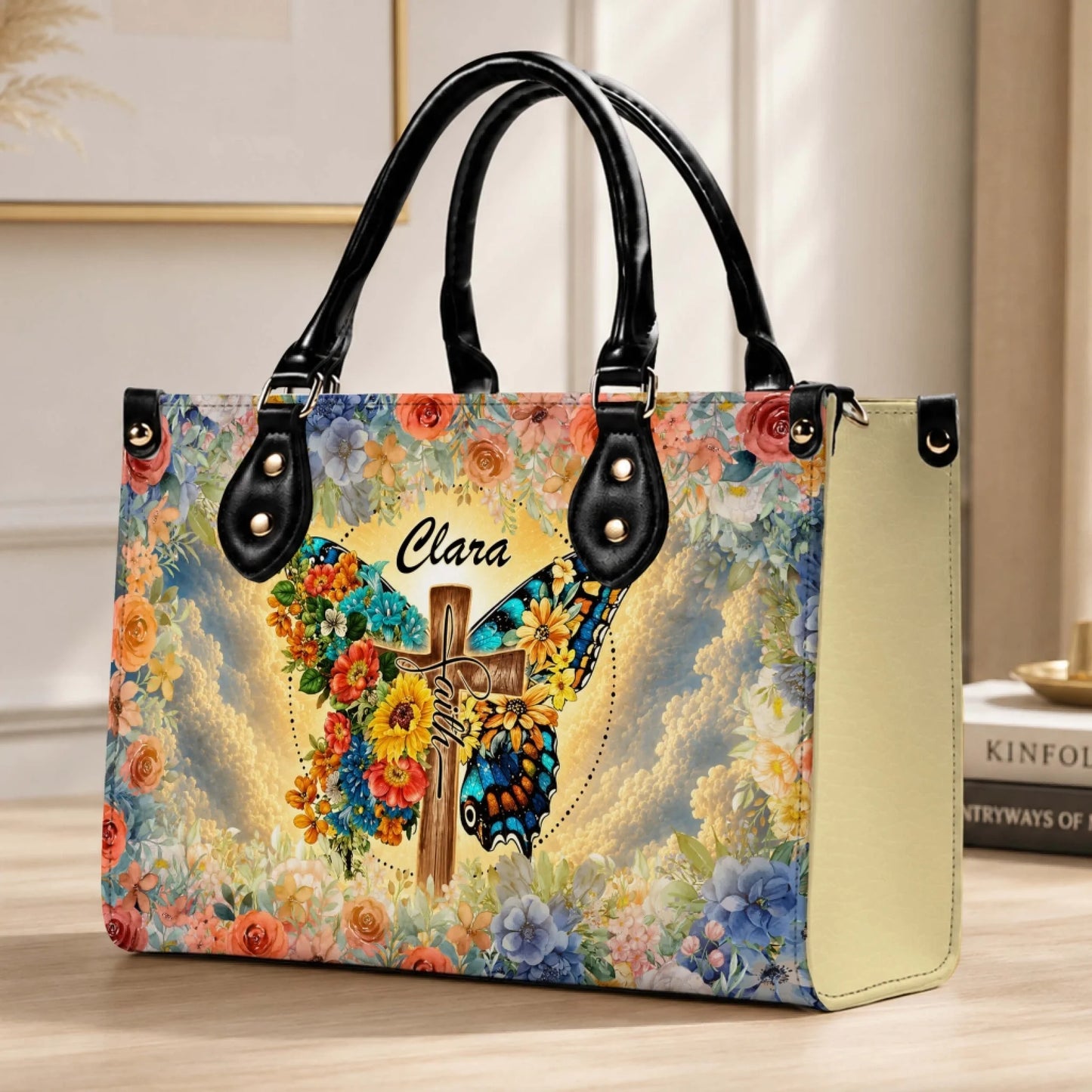 Elegant handbag personalized with the name Clara, featuring a serene butterfly and cross art piece surrounded by a lush floral pattern.