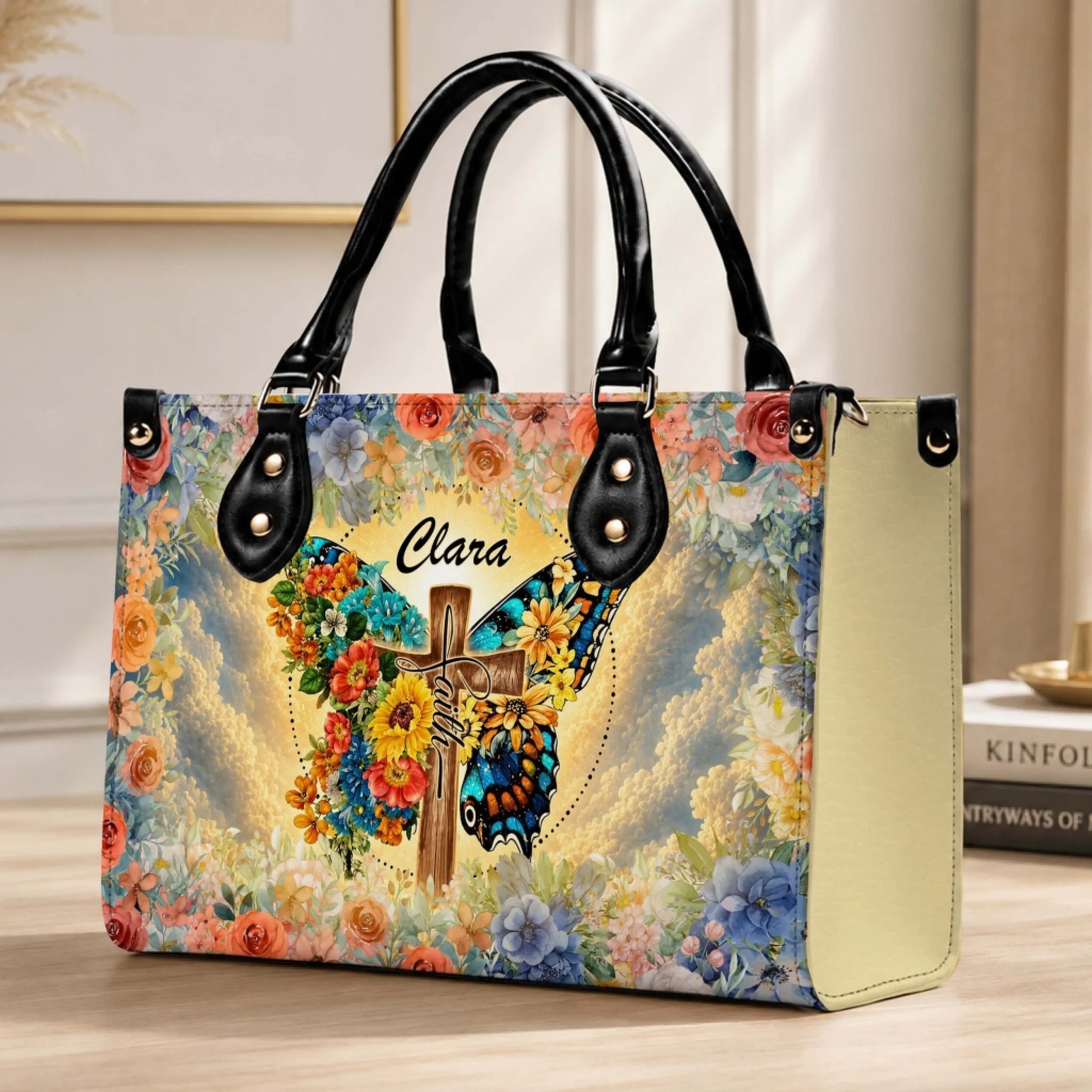 Elegant handbag personalized with the name Clara, featuring a serene butterfly and cross art piece surrounded by a lush floral pattern.