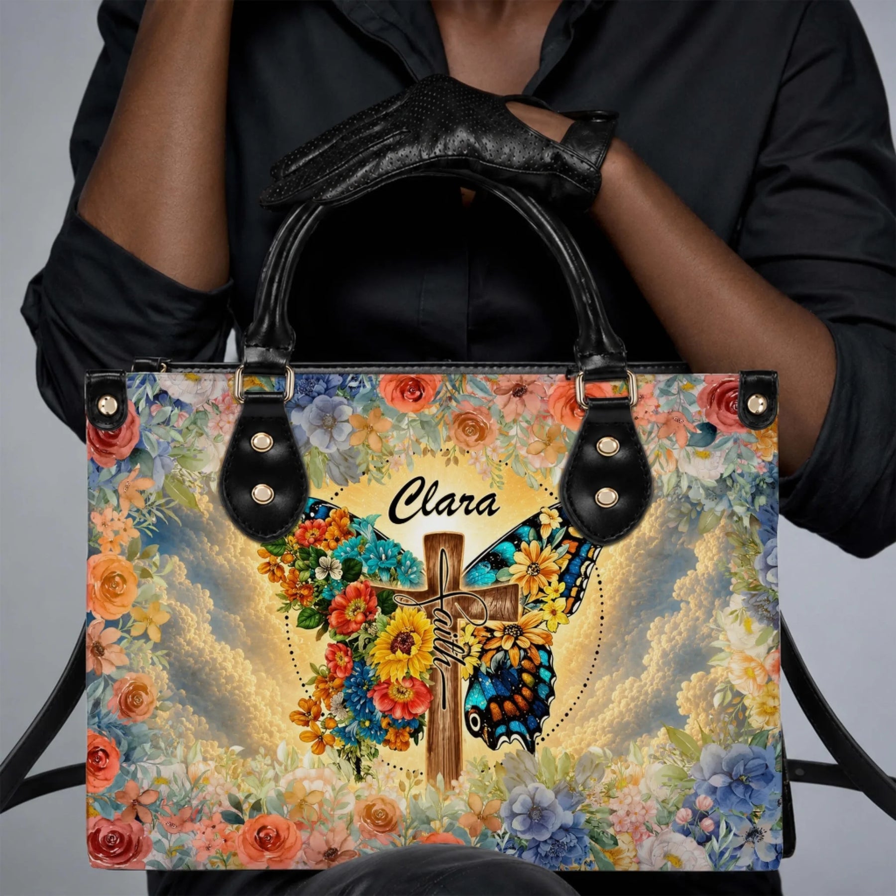 Personalized Clara faith cross butterfly floral print PU leather handbag held by a woman in black.