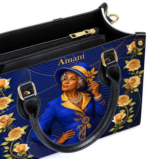 Detail of a custom blue and gold handbag with an elegant woman illustration and personalized Amani text label.