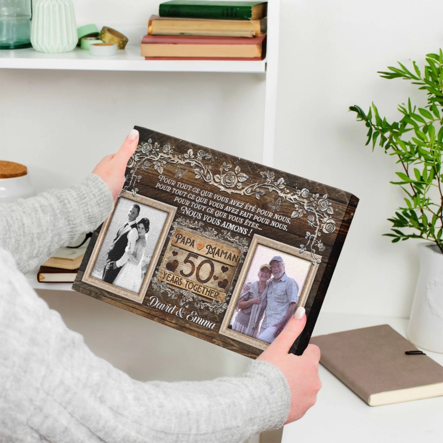 A hands holding a custom 50th anniversary photo canvas with elegant floral art and a rustic wood grain background.